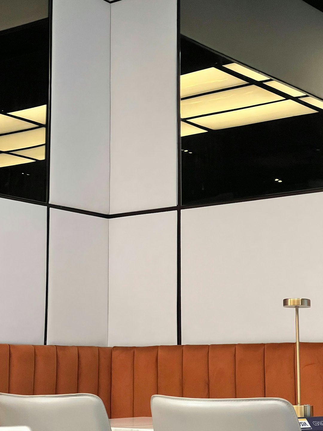 Interno di un ufficio moderno con panca arancione trapuntata e scrivania.