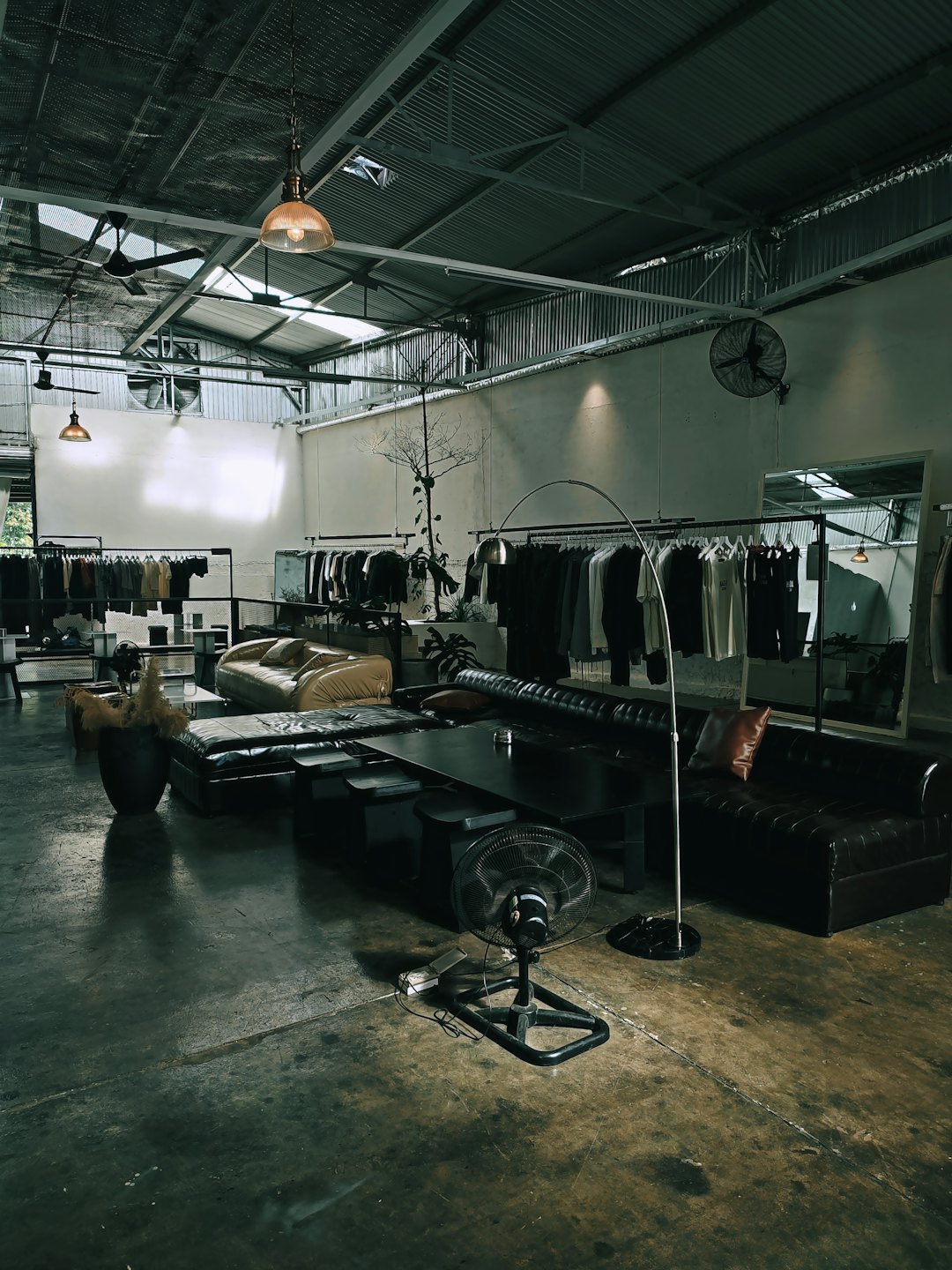 Boutique di abbigliamento contemporanea con scaffali e sedute in pelle su pavimenti in cemento.